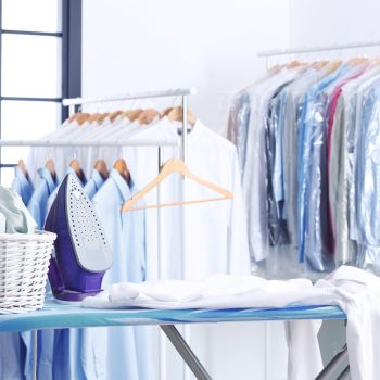 Wicker basket with clothes on ironing board at dry-cleaner's